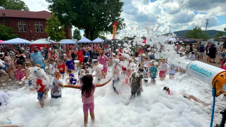 A big crowd of kids playing in foam at a community festival