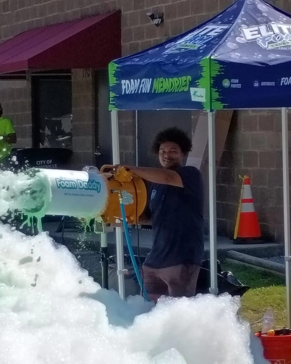 An Elite Foam Experiences pro running the foam cannon under the branded tent at a Chattanooga foam party