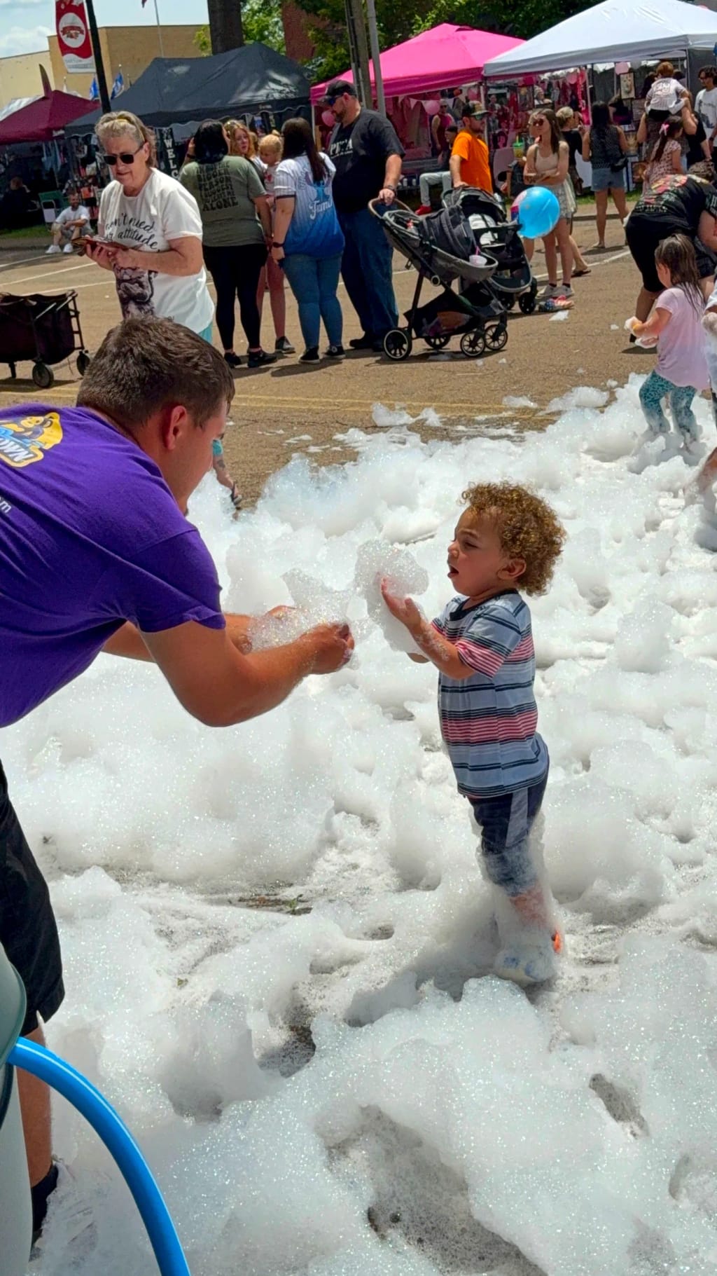 An Elite Foam Experiences team member handing foam to a delighted toddler
