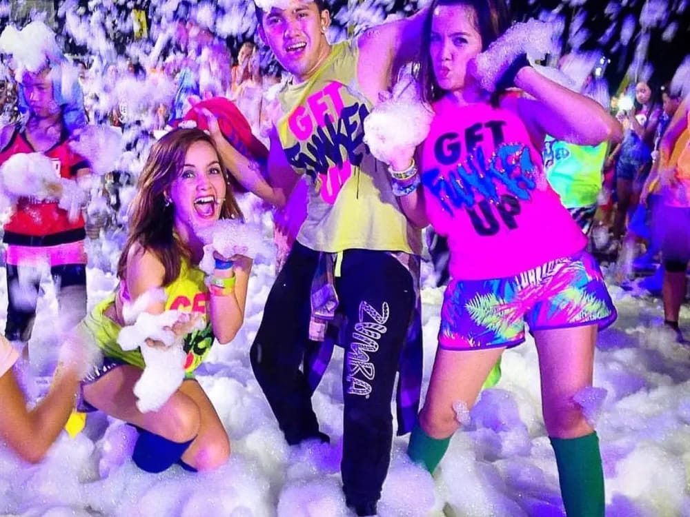 Adults in neon outfits dancing at a glow foam night